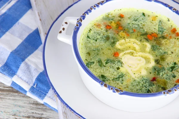 Soupe dans une assiette sur une serviette sur une planche en bois sur une table en bois — Photo