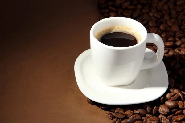 Šálek kávy s kávovými zrny na hnědém pozadí — Stock fotografie