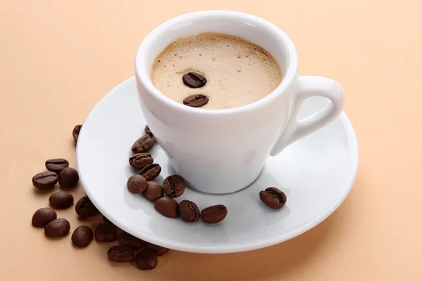 Tasse Kaffee mit Kaffeebohnen auf beigem Hintergrund — Stockfoto