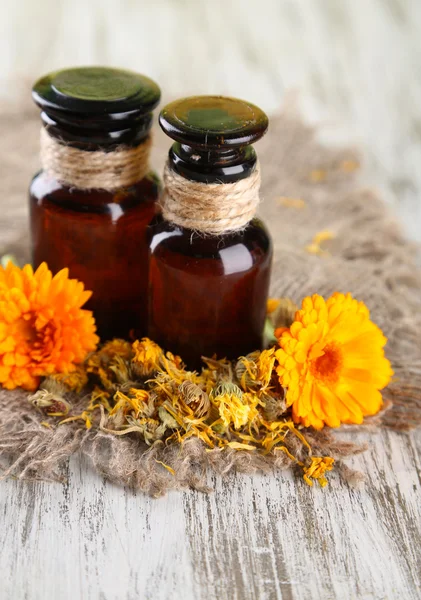 Medicine bottles and calendula flowers on wooden background — Stock Photo, Image