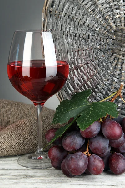 Läckra mogna druvor med glas vin på bordet på grå bakgrund — Stockfoto