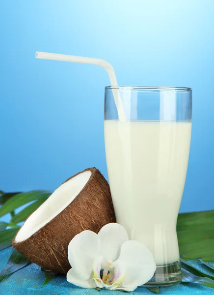 Kokos met glas melk, op blauwe achtergrond — Stockfoto