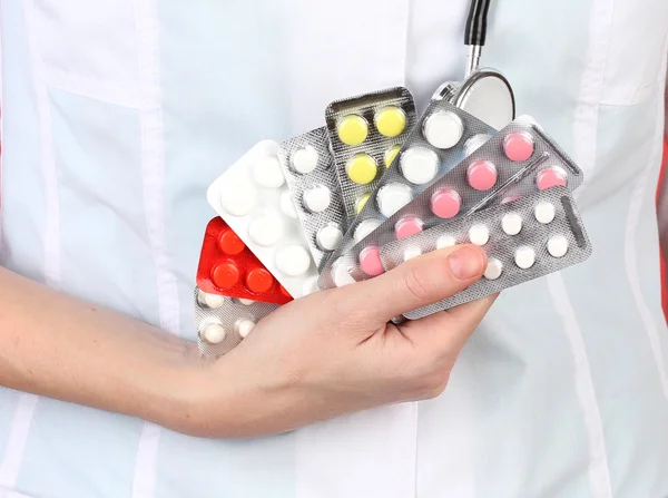 Primer plano de las píldoras de la mano del médico femenino, sobre fondo de color —  Fotos de Stock