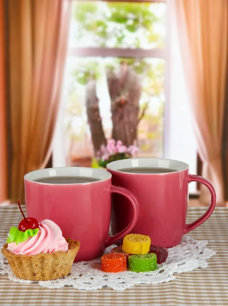 Tasses de thé avec gâteau et bonbons sur la table dans la chambre — Photo