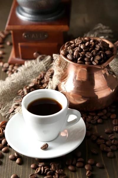 Cup of coffee, pot and grinder on wooden background — Stock Photo, Image