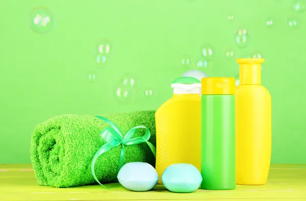 Baby cosmetica, handdoek en zeep op houten tafel, op groene achtergrond — Stockfoto