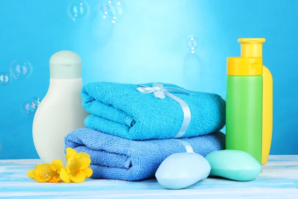 Cosmetici per bambini, asciugamani e sapone su tavola di legno, su sfondo blu — Foto Stock