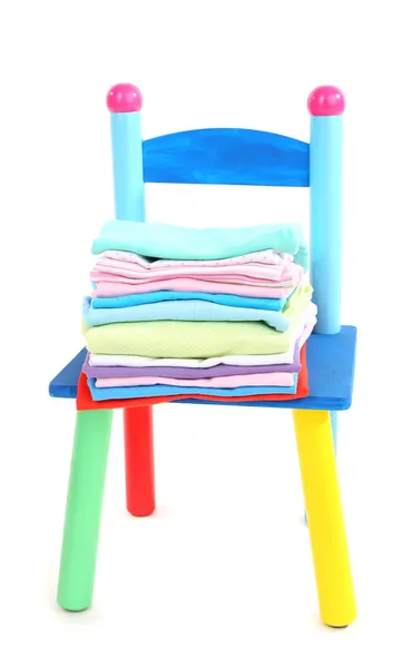 Маленький и цветной стул с детской одеждой, изолированной на белом — стоковое фото