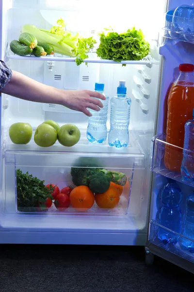 Kvinnans hand når ut för mat från kylskåp, närbild — Stockfoto