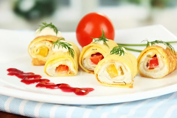 Rotoli d'uovo con crema di formaggio e paprika, su piatto, su sfondo brillante — Foto Stock