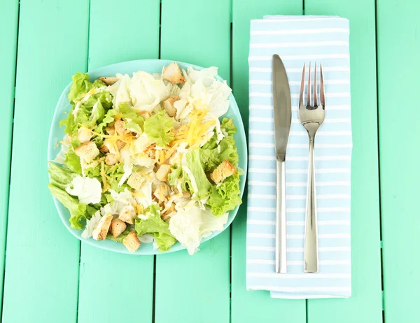 Caesar-Salat auf blauem Teller, auf farbigem Holzhintergrund — Stockfoto