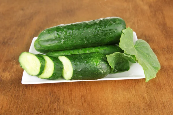 Läckra gröna gurkor på färg Servett, trä bakgrund — Stockfoto
