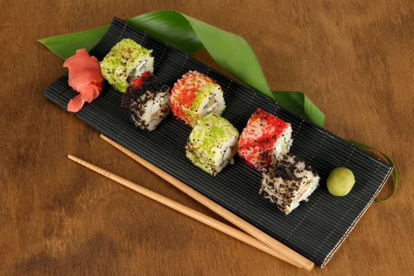 Leckeres Maki-Sushi - Rolle auf Matte auf braunem Hintergrund — Stockfoto