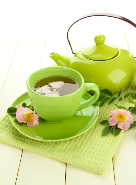 Tasse und Teekanne Kräutertee mit hippen Rosenblüten auf weißem Holztisch — Stockfoto