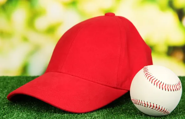 Red peaked cap on grass on natural background