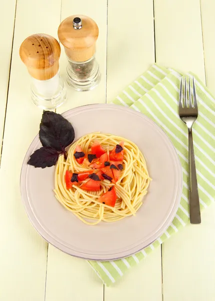 Spaghetti mit Tomaten und Basilikumblättern auf Serviette auf Holzgrund — Stockfoto