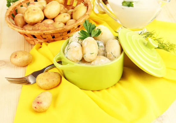 Tender young potatoes with sour cream and herbs in pan on wooden table close-up — Stock Photo, Image