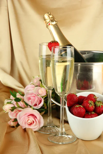 Romantic still life with champagne, strawberry and pink roses, on color fabric background — Stock fotografie