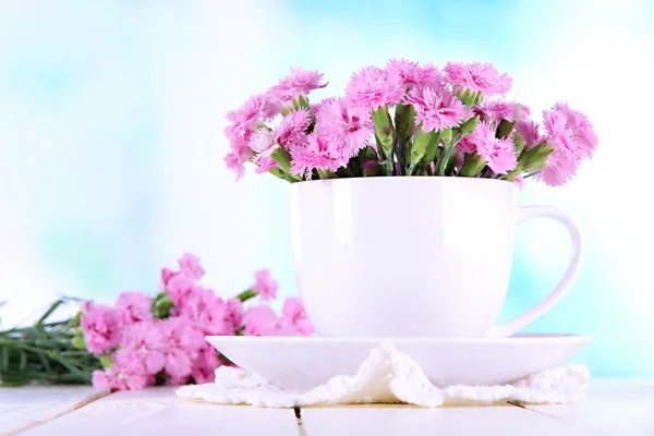 Muchos pequeños dientes de color rosa en la taza en la mesa de madera en el fondo de la ventana — Foto de Stock