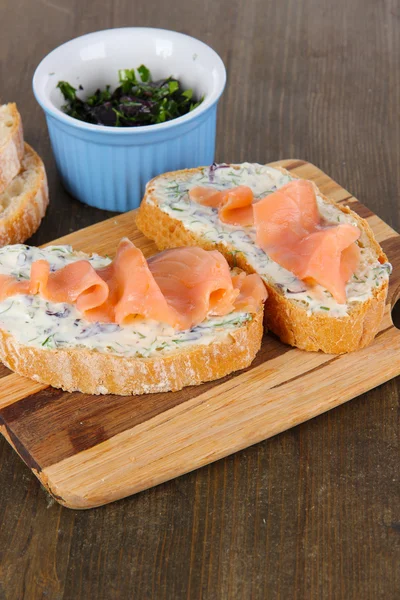 Rybí sendviče na prkénko na dřevěný stůl — Stock fotografie