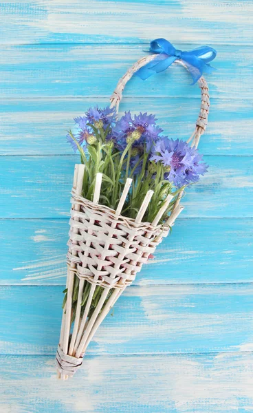 Beautiful bouquet of cornflowers in basket on blue background — Stock Photo, Image