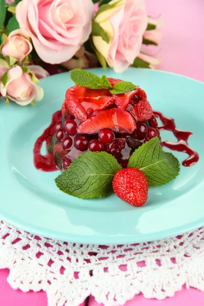 Sabroso postre de gelatina con bayas frescas, sobre fondo de rosas rosadas — Foto de Stock