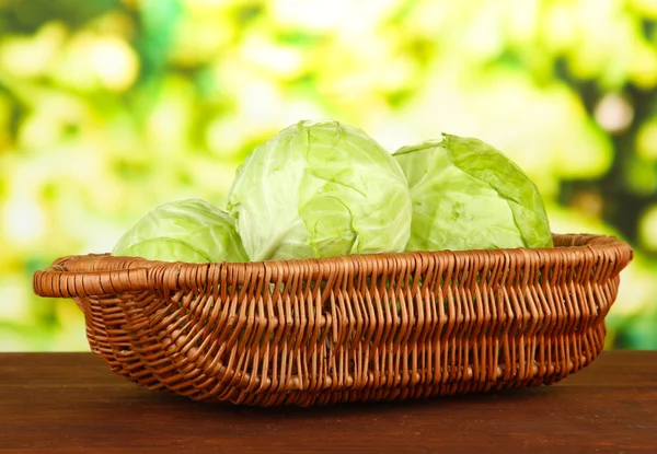 Green cabbage in wicker basket, on bright background — Stock Photo, Image