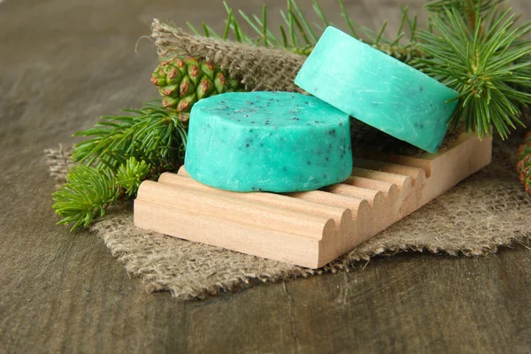 Handgjord tvål och gröna kottar på trä bakgrund — Stockfoto