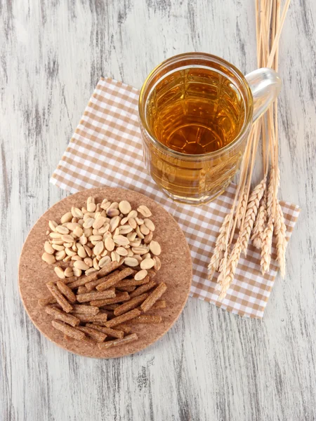 Beer in glass crunches, and nuts on napkin on wooden table — Stock Photo, Image