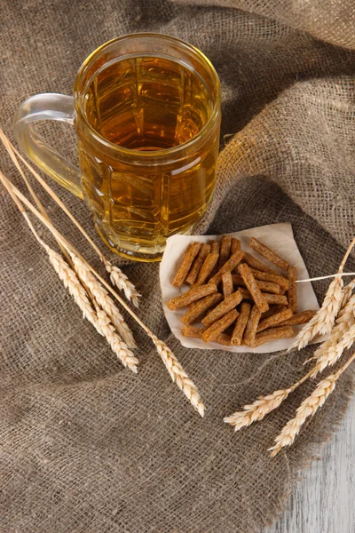 Beer in glass and crackers on bagging on wooden table — Stock Photo, Image