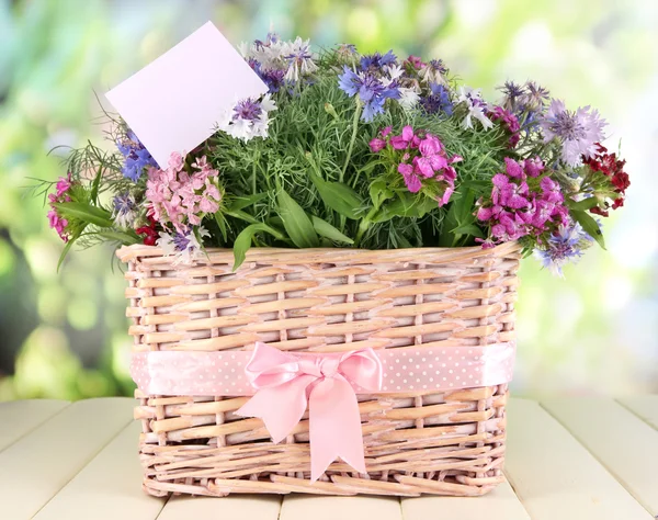 Krásná kytice v košíku na dřevěný stůl na přírodní pozadí — Stock fotografie