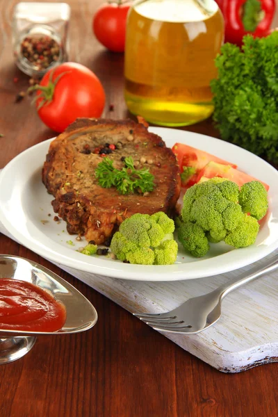 Шматок смаженого м'яса на тарілці на дерев'яному столі крупним планом — стокове фото