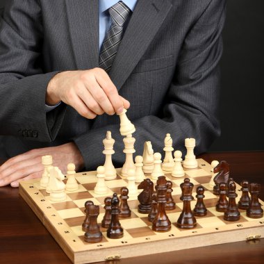 siyah arka plan üzerinde satranç oynayan genç iş adamı