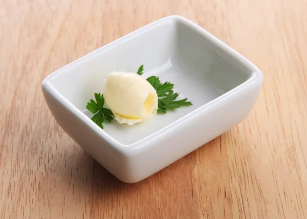 Boucle de beurre sur assiette, sur table en bois — Photo