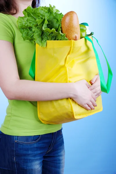 Dívka s nákupní taškou na modrém pozadí — Stock fotografie