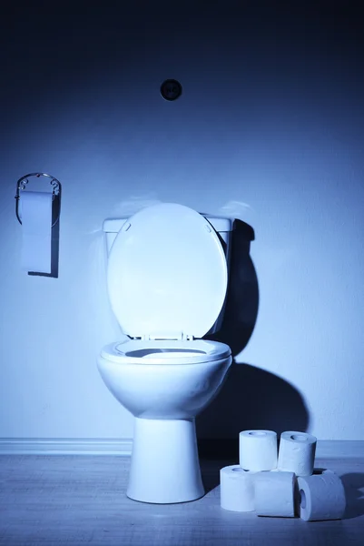 Toilet bowl and toilet paper in a bathroom with blue light — Stock Photo, Image