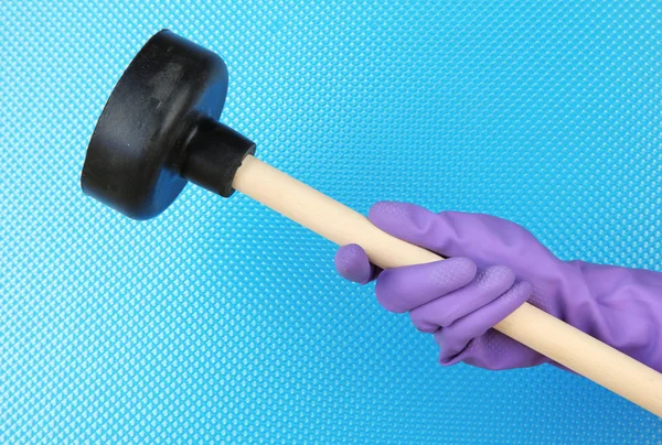 Toilet plunger in hand on blue background — Stock Photo, Image