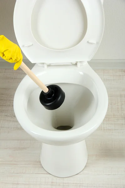 Woman uses a plunger to unclog a toilet bowl in a bathroom — Stock Photo, Image