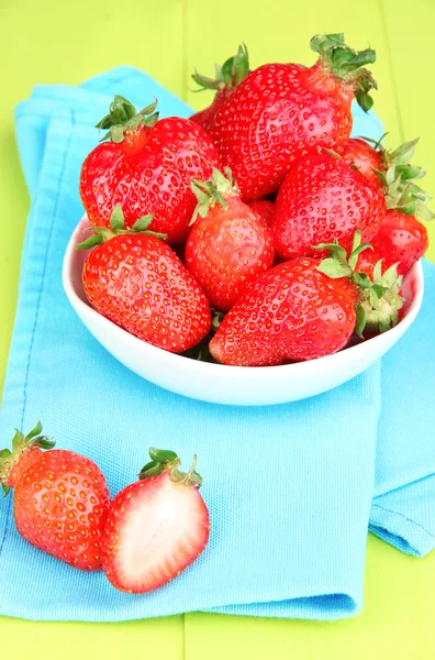 Verse aardbeien in kom op groene houten achtergrond — Stockfoto