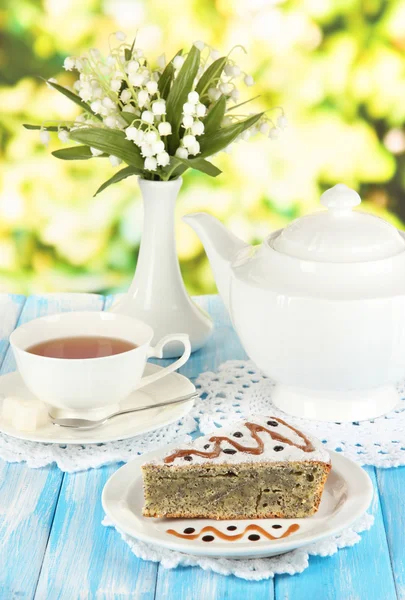 Delicioso pastel de semillas de amapola con taza de té en la mesa sobre fondo brillante —  Fotos de Stock