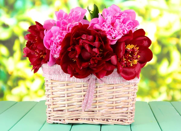 Belles pivoines dans le panier en osier sur la table sur fond lumineux — Photo