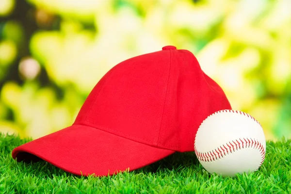 Red peaked cap on grass on natural background
