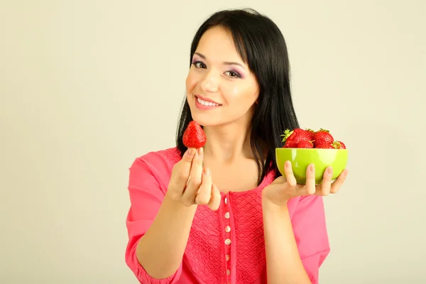 Hermosa joven con fresas sobre fondo gris —  Fotos de Stock