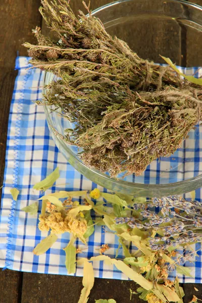 Φαρμακευτικά φυτά σε γυάλινο μπολ σε χαρτοπετσέτα στο ξύλινο τραπέζι — Φωτογραφία Αρχείου