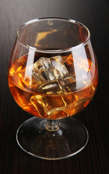 Brandy glass with ice on wooden background — Stock Photo, Image