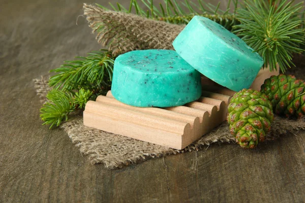 Jabón hecho a mano y conos de pino verde sobre fondo de madera —  Fotos de Stock