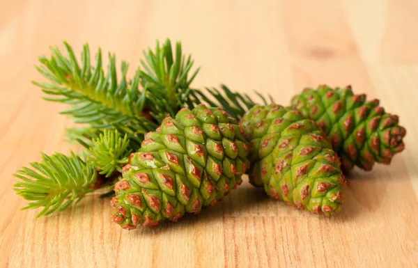 Green cones and fir tree on wooden background — Stock Photo, Image