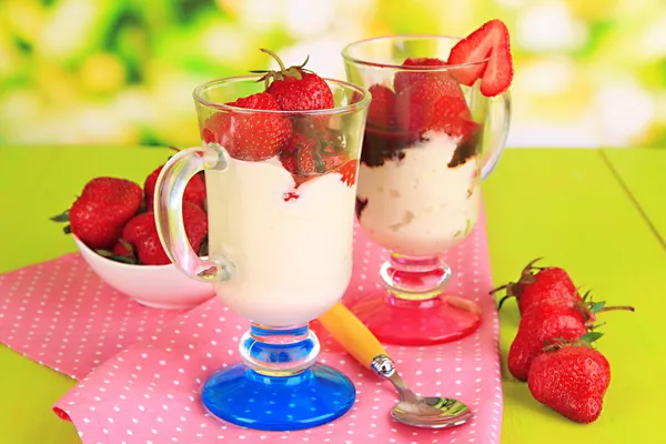 Deliziosi dessert alla fragola in vaso di vetro su tavolo di legno su sfondo naturale — Foto Stock