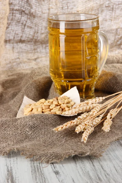 Beer in glass and nuts on bagging on wooden table — Stock Fotó