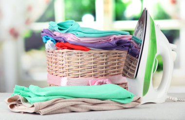 Buharlı Ütü ve parlak arka plan üzerinde elbise ile hasır sepet